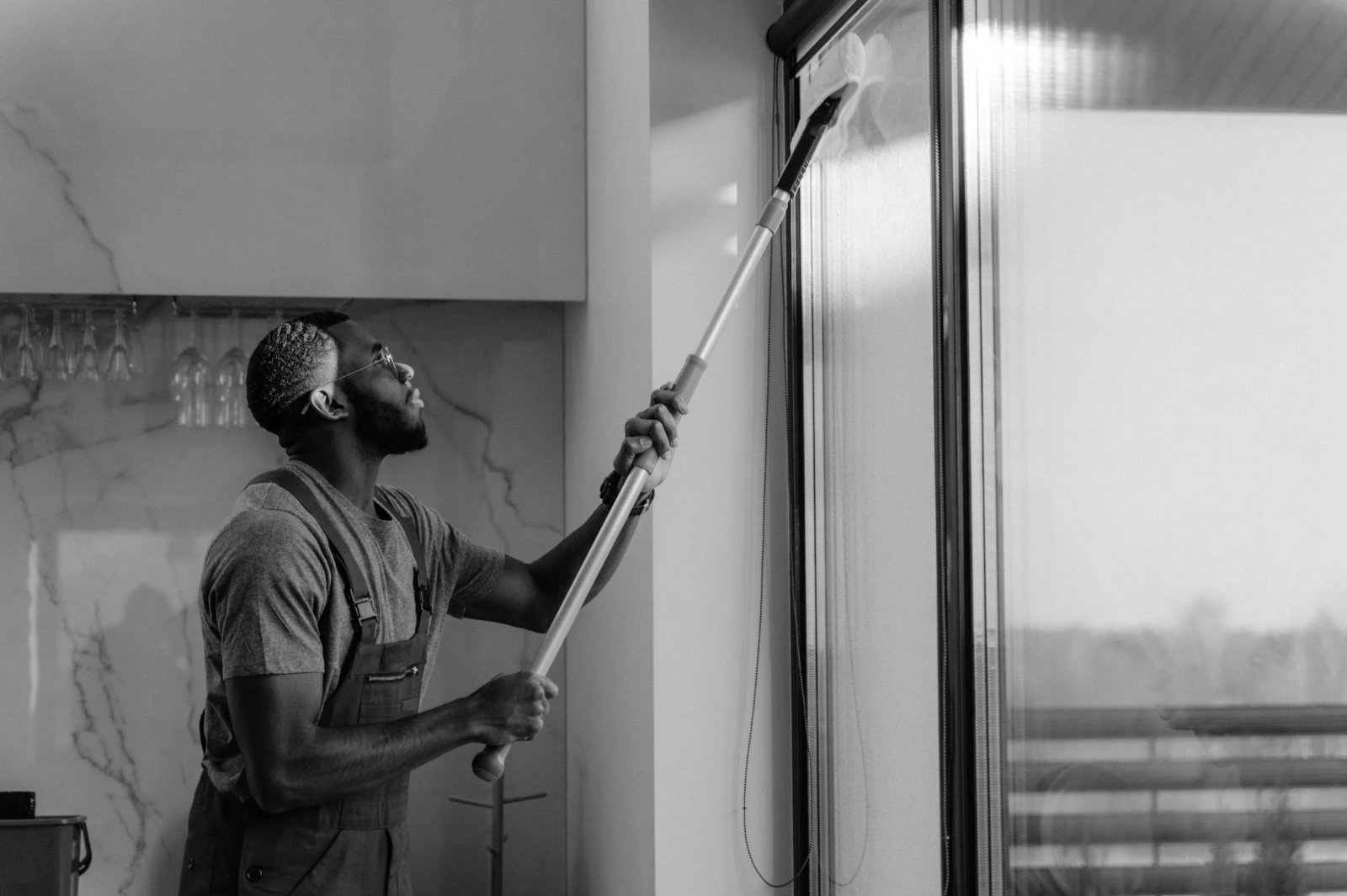 Professional cleaning team wiping desks and glass partitions in a bright modern office.